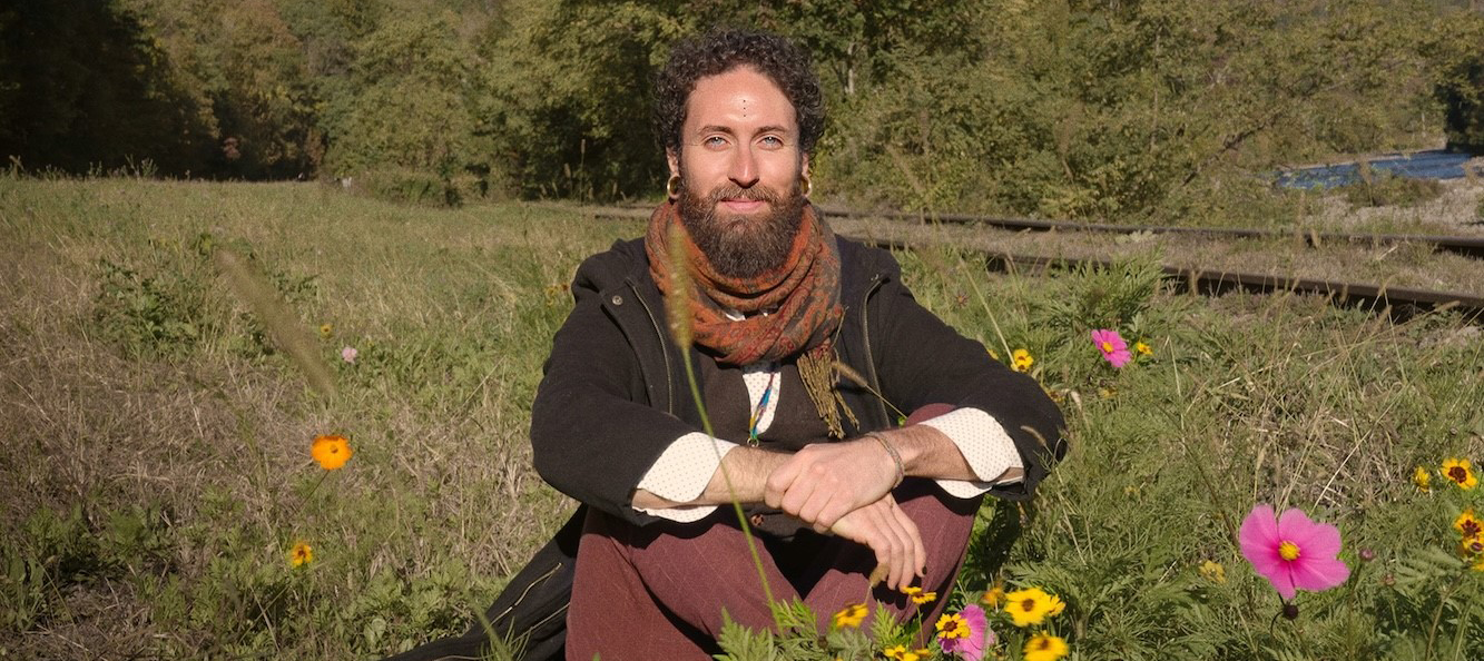 Food Therapy: How to Eat for Your Nervous System Luis Mojica sitting in a field with grass and flowers.