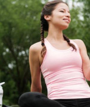 Young beautiful woman sitting outside smiling and holding a book